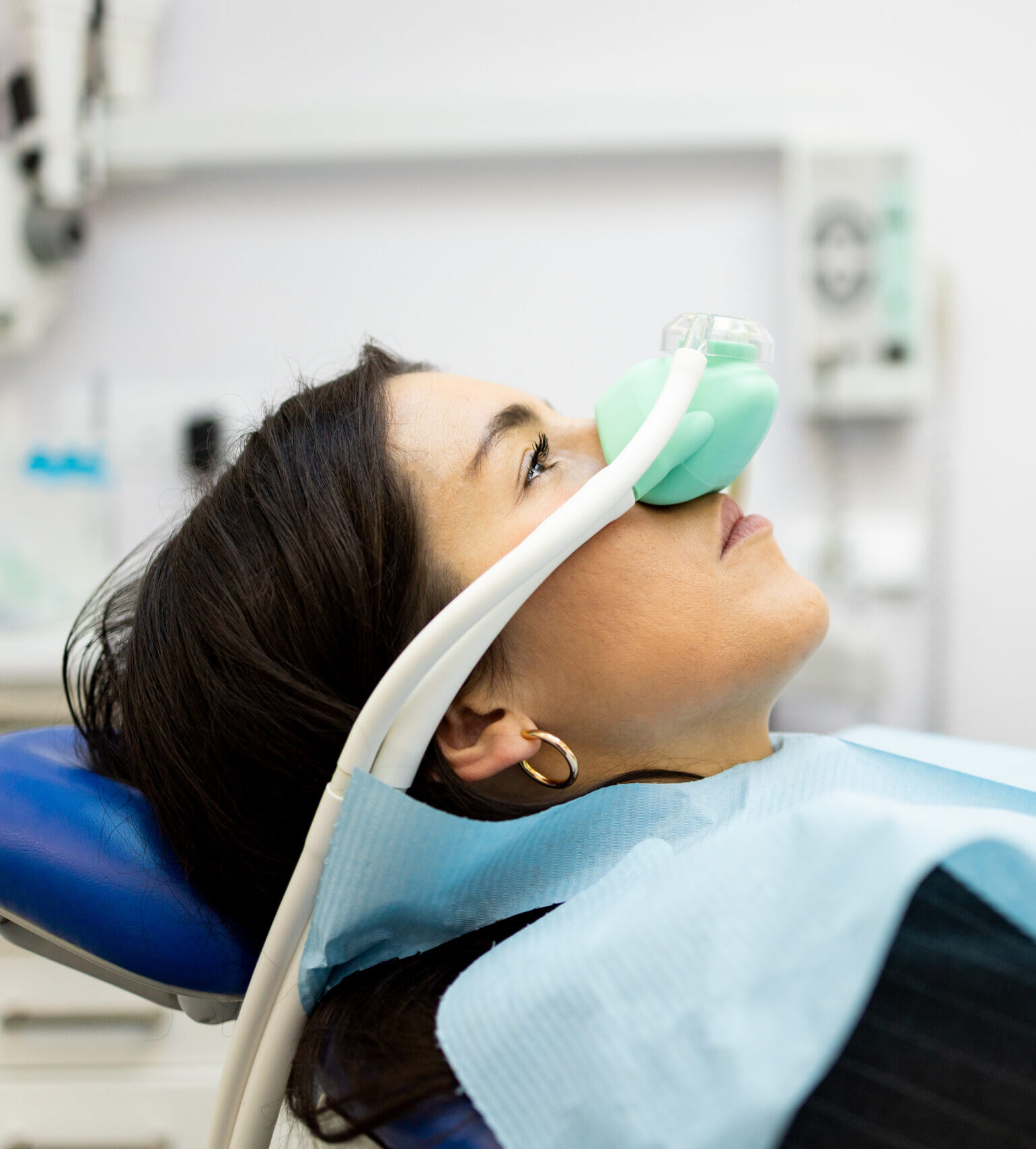 An adult woman sits in a dentist's office wearing a nasal mask to inhale nitrous oxide. Dentist fear concept. Feeling of relaxation with laughing gas. Visit a dentist with relaxation.