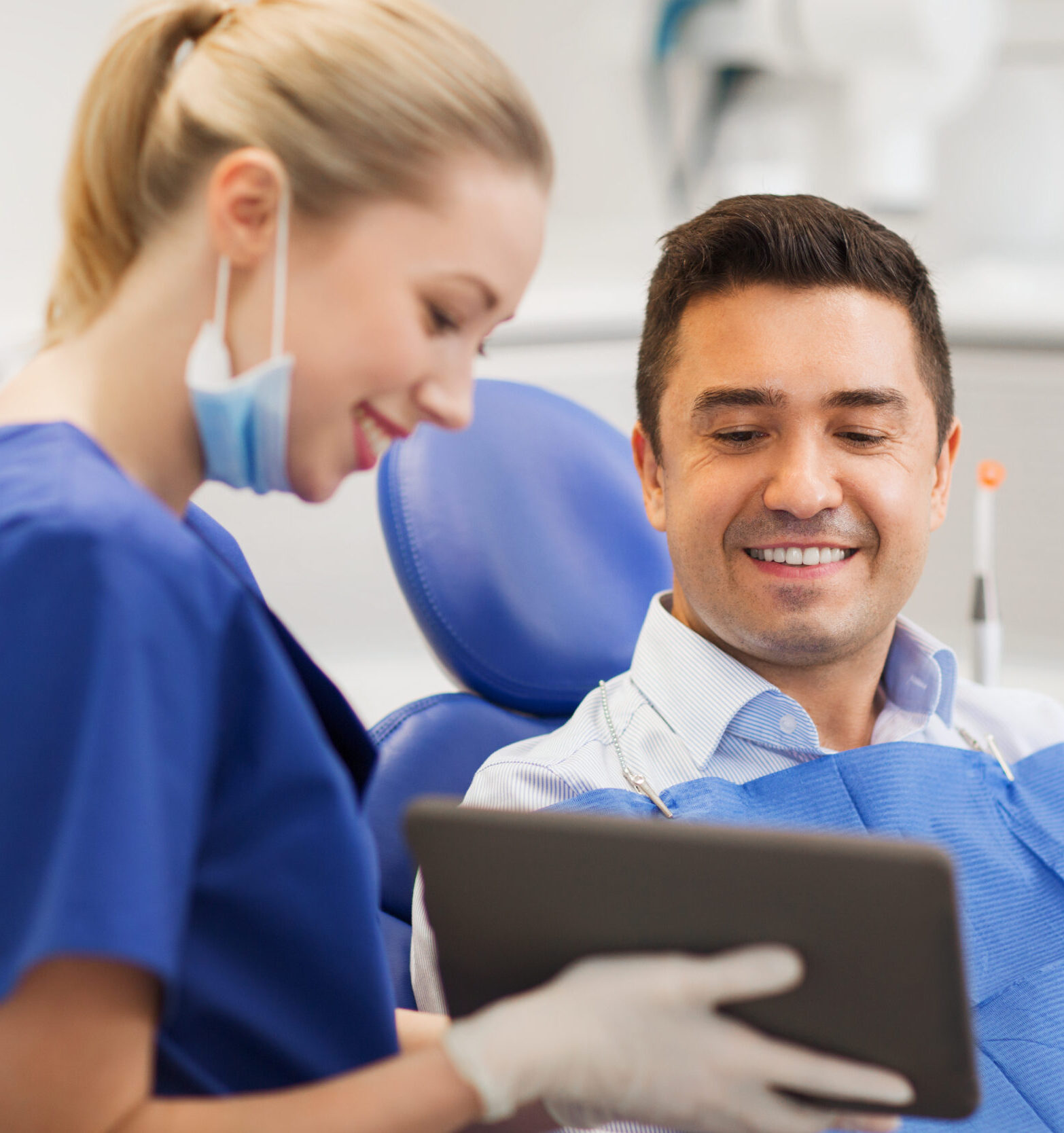 people, medicine, stomatology and health care concept - happy female dentist showing tablet pc computer to male patient at dental clinic office